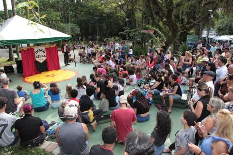 publico assiste espetáculo sentado  no chão #paratodosverem