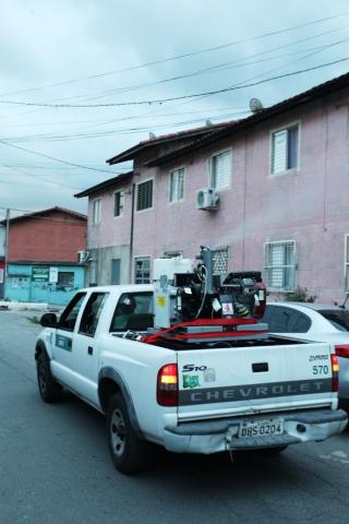 Maquinário em caçamba de veículo lança fumaça em rua. #Paratodosverem