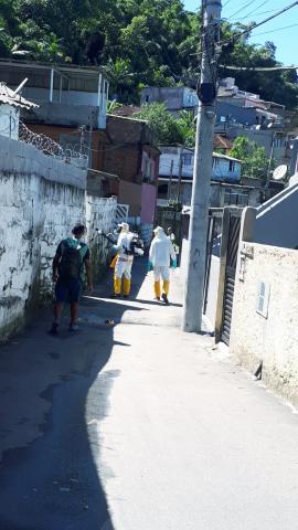 homens que aplicam inseticida caminham por rua. #paratodosverem