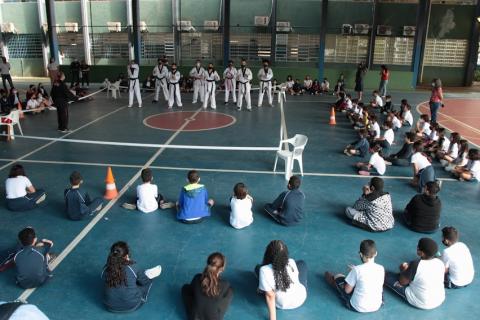 Lutadores de apresentando e estudantes assistindo sentados #paratodosverem