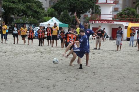 lance envolvendo três jogadores numa dividida com a bola. Ao fundo outros jogadores assistem. #paratodosverem