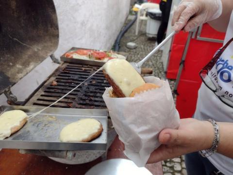 Pessoa coloca hambúrguer com queijo dentro de pão. #paratodosverem