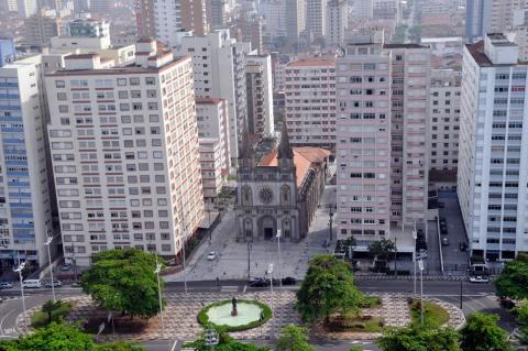 vista aérea de trecho do bairro, com praça, igreja e prédios. #paratodosverem