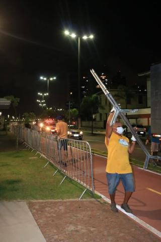 Homem carrega grade. Ao fundo, há várias já dispostas ao longa do trecho. #Paratodosverem