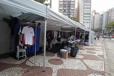 Barracas de apoio à produção, com roupas penduradas em cabides, estão montadas no calçadão lateral da orla. #partodosverem