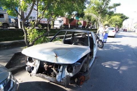 carro parcialmente destruído está estacionado em via ao lado de canal. #paratodosverem
