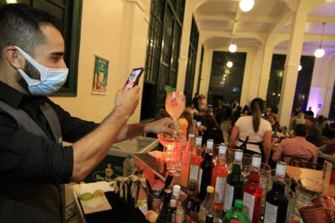 Barman tira foto do espaço com várias bebidas a sua frente #paratodosverem