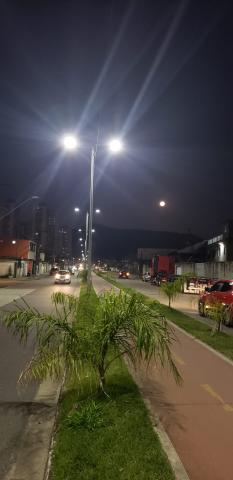 vista com canteiro central no centro da foto e luminárias nos postes ao fundo. @paratodosverem