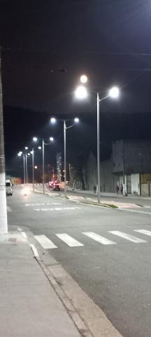 vista geral da rua com luminárias acesas nos postes. #paratodosverem