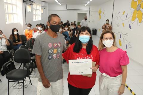 três pessoas posam para foto. Uma delas segura um certificado. #paratodosverem