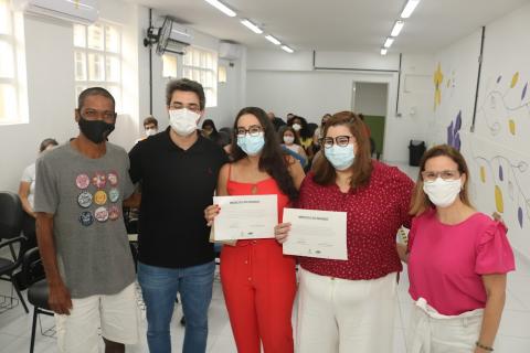 Cinco pessoas posam para foto. Duas delas seguram certificados. #paratodosverem