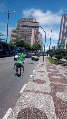 Homens pintam guias de calçada na avenida da praia #paratodosverem