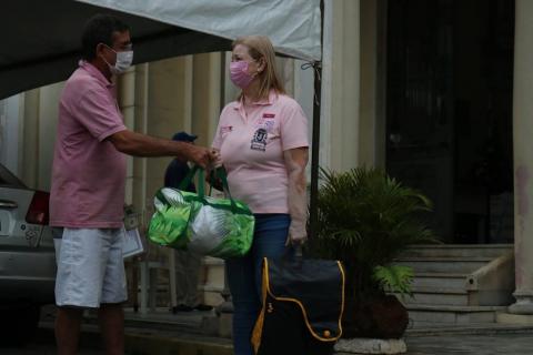 homem entrega sacola a mulher #paratodosverem