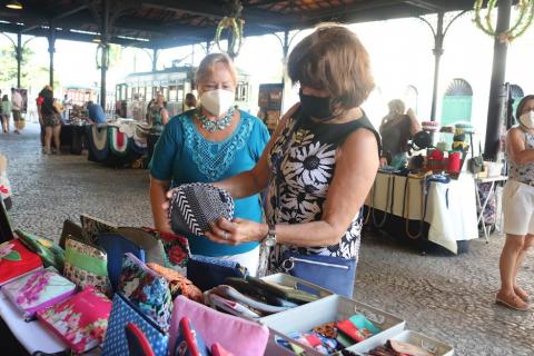 mulheres olham produtos em feira #paratodosverem