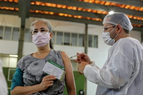 mulher vacinada no braço enquanto mostra cartão #paratodosverem