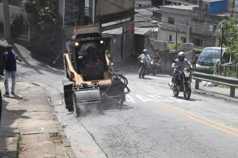 minicarregadeira realiza serviço em trecho da via e moto passa ao lado #paratodosverem