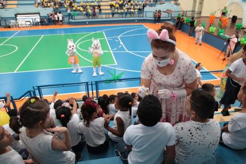 mulher vestida de coelha pinta crianças em arquibancada #paratodosverem