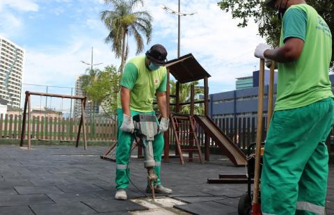 homens colocando piso de borracha em playground #paratodosverem