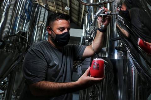 homem retira cerveja vermelha de equipamento #paratodosverem