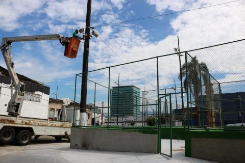 praça e homem em cima de guindaste arrumando iluminação #paratodosverem