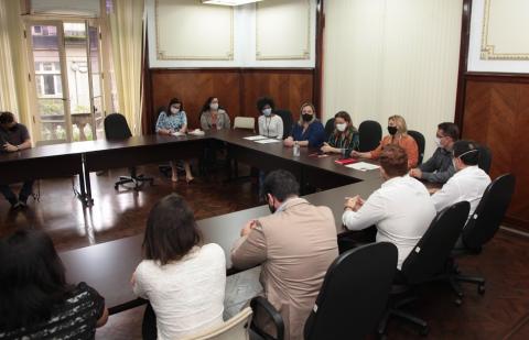 Pessoas sentadas em sala para assinatura do convênio #paratodosverem