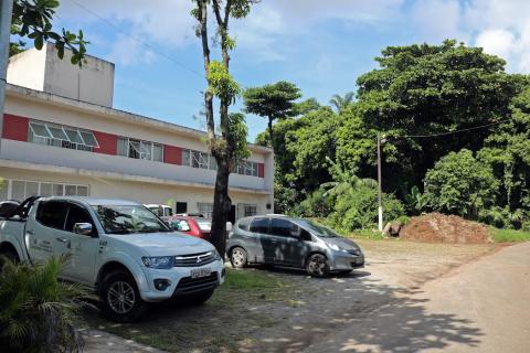 terreno com prédio ao fundo e carros estacionados #paratodosverem