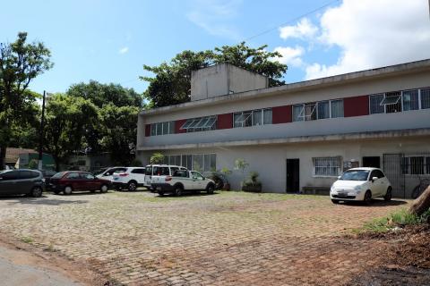 terreno com prédio ao fundo e carros estacionados #paratodosverem