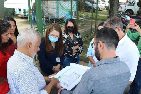 autoridades olham para papel com planta do local #paratodosverem