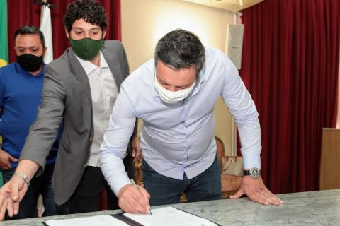 O prefeito assina a documento. #paratodosverem