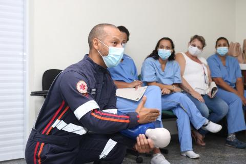 técnico mostra técnica em boneco, observado por enfermeiras #paratodosverem 