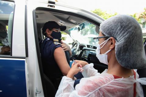 guarda em viatura mostra o braço para vacinar #paratodosverem 
