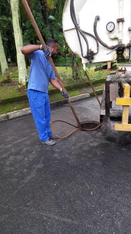 hmem limpa rede de drenagem com poço de visita aberto no meio de pista. #paratodosverem