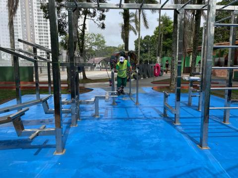 homem está em pé, fazendo serviços na área dos equipamentos de calistenia. #paratodosverem