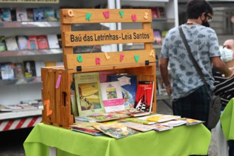 estrutura para quem quiser pegar livros,com estande infantil em primeiro plano. #paratodosverem