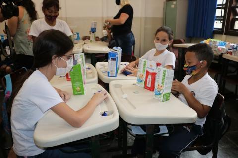 Estudantes com caixas de leite na sala de aula #paratodosverem