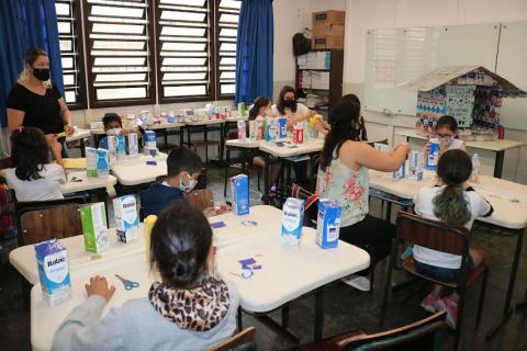 Estudantes com caixas de leite na sala de aula #paratodosverem