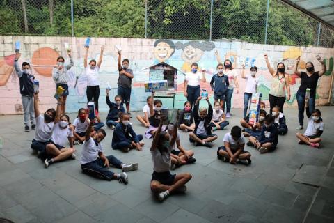 Estudantes com caixas de leite no pátio #paratodosverem