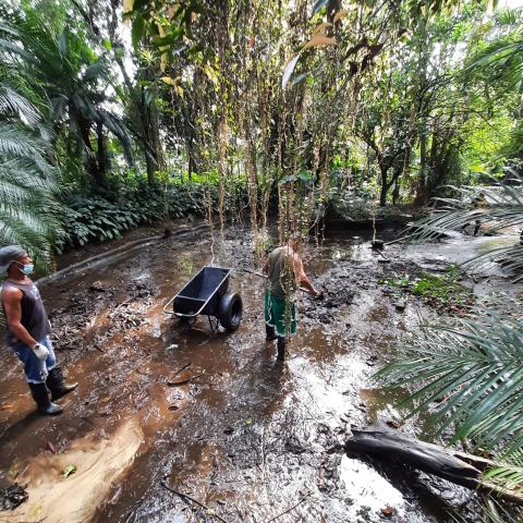 homens estão dentro de lago vazio em meio a vegetação. #paratodosverem