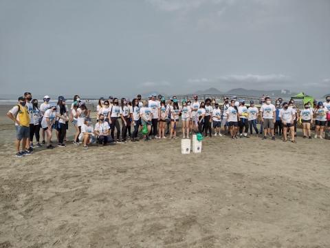 grupo de voluntários e todos os participantes do mutirão posa para foto na faixa de areia. #paratodosverem