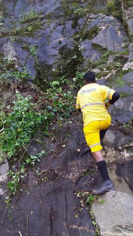 Homem escala morro limpando #paratodosverem