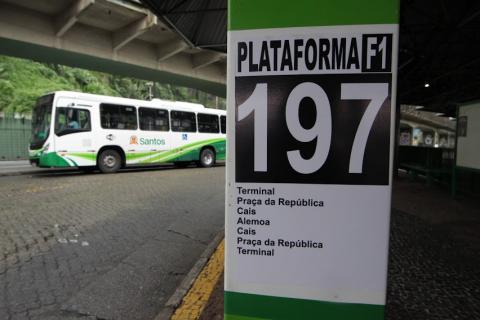 toten onde está afixado número de linha 197, com o respectivo itinerário na parte de baixo.Ao fundo, um ônibus municipal. #paratodosverem