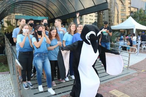 pinguim posa para foto com pessoas na porta #paratodosverem