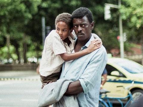 cena de marighela, com o personagem principal segurando uma criança no colo na rua. #paratodosverem