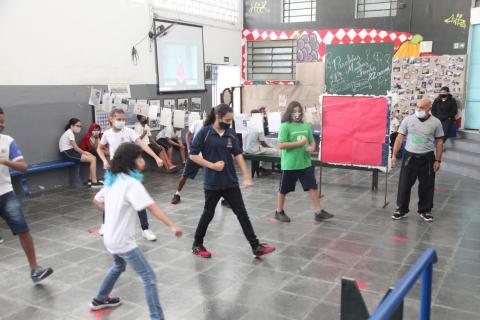 alunos enfileirados no pátio fazem coreografia. #paratodosverem