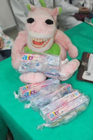 mesa com boneco de pelúcia e alguns kits de higiene bucal. #paratodosverem
