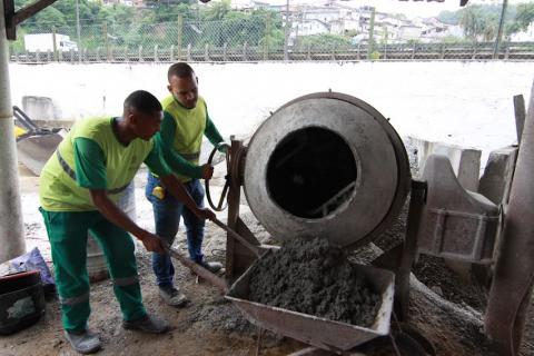 homens preparam massa para as muretas diante de betoneira. #paratodosverem