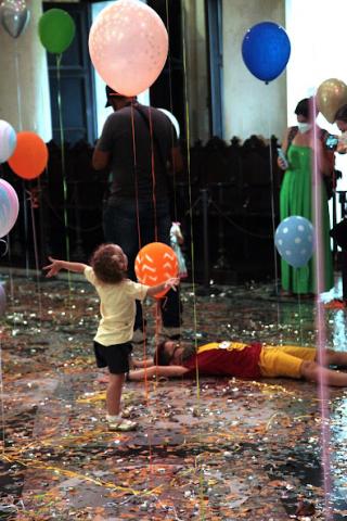 Criança brinca com balão e outra deita no chão. #pratodosverem