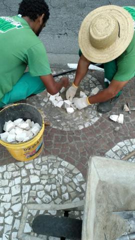 dois homens agachados recuperam piso de mosaico. #paratodosverem