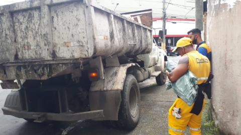 caminhão ao lado de funcionários de limpeza uniformizados. #paratodosverem