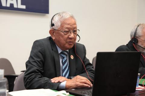 o representante da Associação Japonesa de Santos está diante de um laptop. ele usa um fone de ouvido com microfone acoplado. #paratodosverem